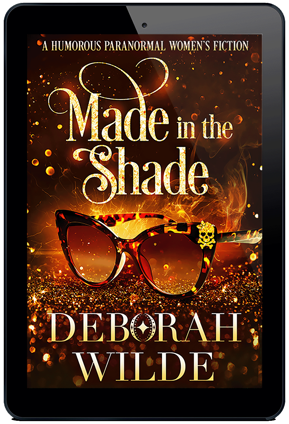 A gold ebook cover for "Made in the Shade" by Deborah Wilde. A pair of tortoise shelled sun glasses sits on a field of sparkles with sparks and smoke rising from it. On the top corner of the glasses is a glittery skull with heart shaped eye sockets and a large glittery bow on its head.