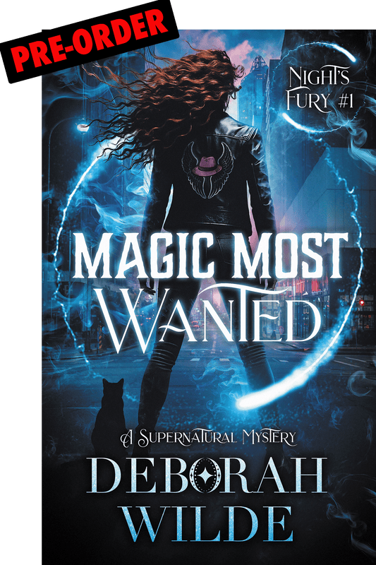 Book cover of 'Magic Most Wanted' by Deborah Wilde with a woman with long brown wind-blown hair. A black cat and glowing effects light up a city street.